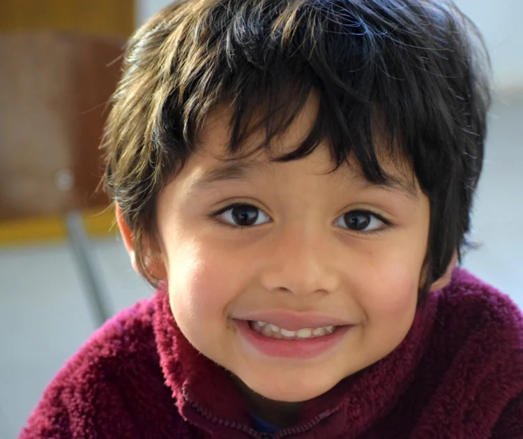 A smiling child in a burgundy sweater